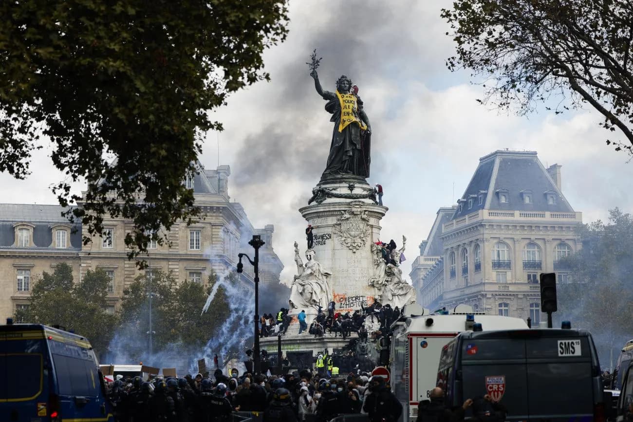 Protesters climb the monument on Paris’s Place de la République amid tear gas and riot police vans, October 17, 2026. Photo: Geoffroy Van der Hasselt / AFP (via LCP)
