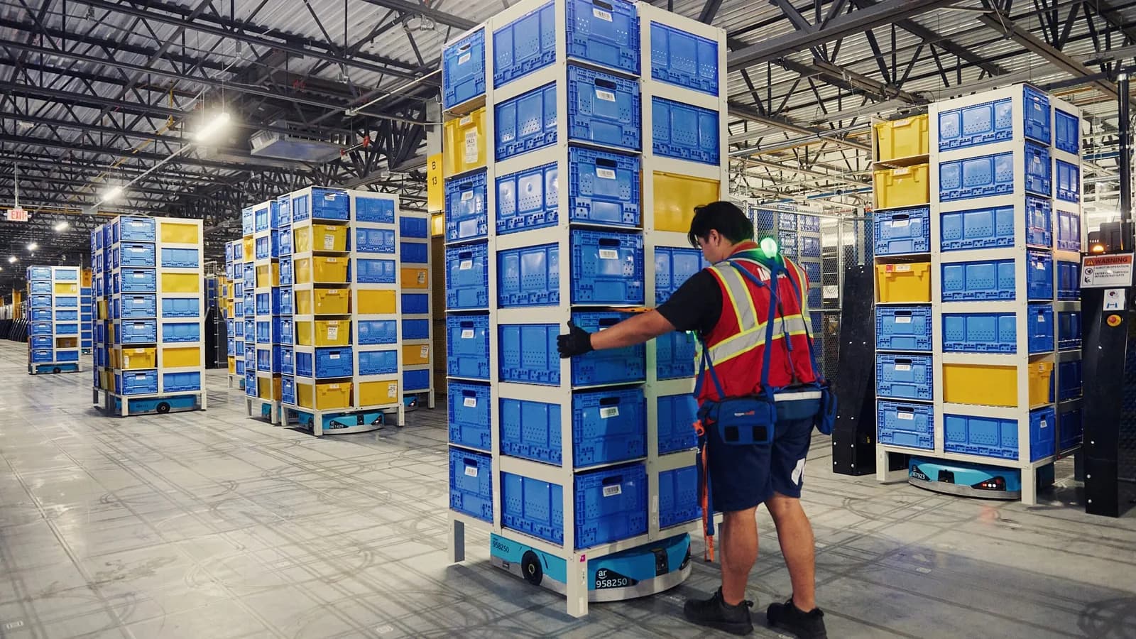 Wheeled mobile robots move tall inventory pods inside an Amazon fulfillment center
