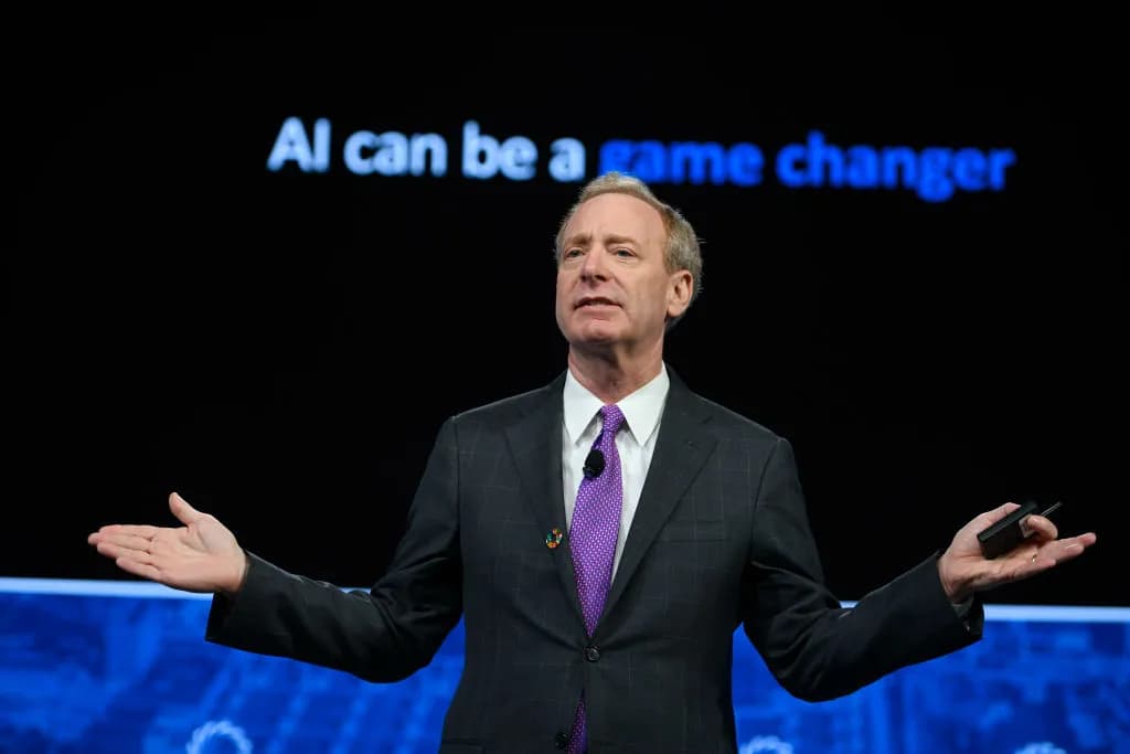 Microsoft President Brad Smith speaking on stage in front of a slide reading “AI can be a game changer”